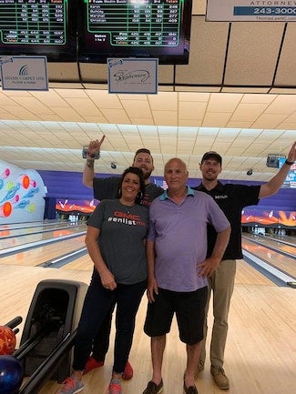 Four people posing for a photo at a bowling alley