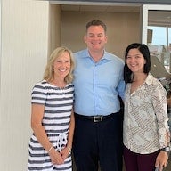 Three people, a man and two women, smiling together indoors.