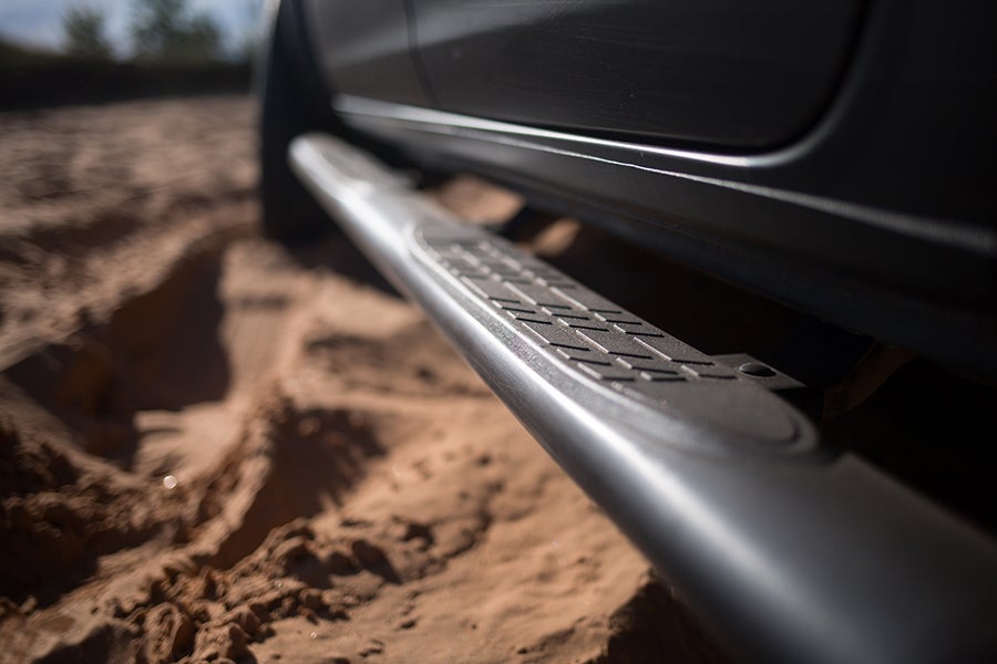 Close-up of a side step rail on an off-road vehicle in sand.